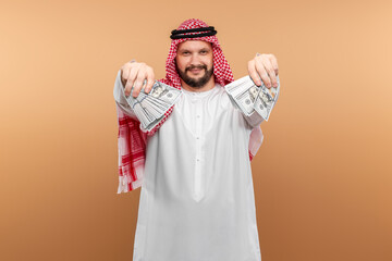Arab man businessman in national clothes is holding dollars in his hands. Business concept in the middle east, oil sale, investment.