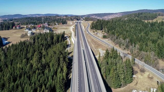 Old road and new highway from Krakow to Zakopane in Poland, called Zakopianka with viaducts, elevated crossroads and cars. Aerial 4K video in winter
