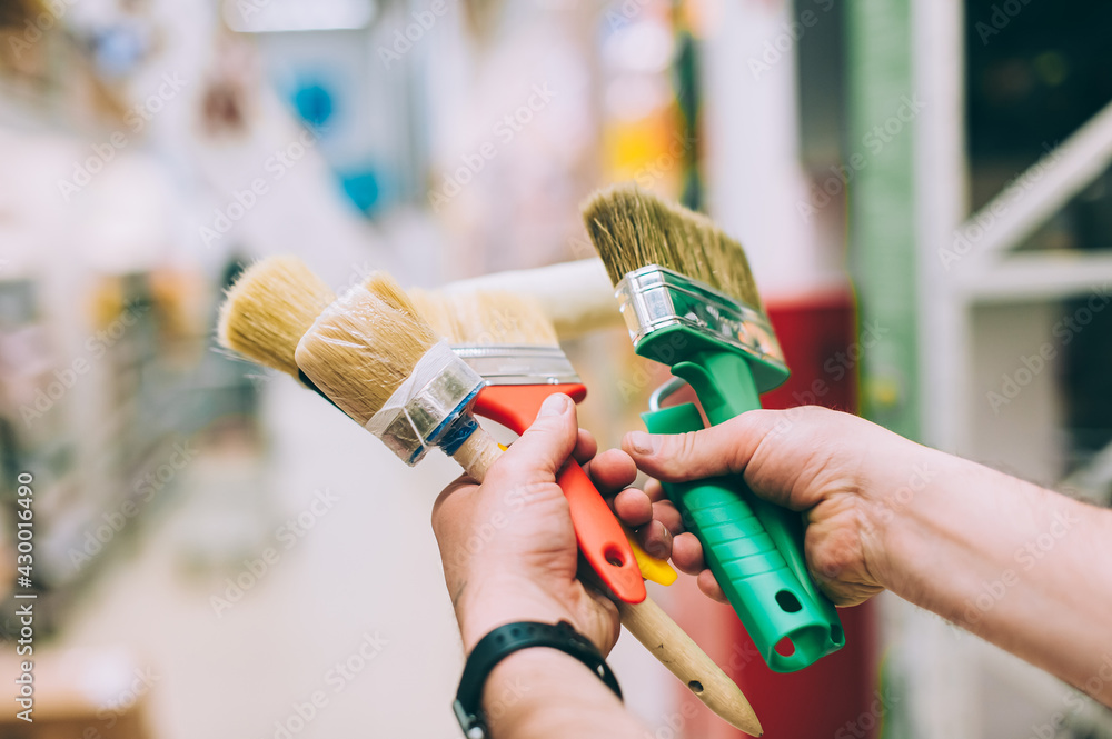 Wall mural A man in a hardware store holds a set of brushes and rollers for paint and decor.