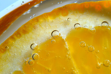 a slice of orange covered with bubbles lies in a glass of sparkling water. Close-up.
