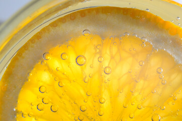 Fototapeta na wymiar a slice of orange covered with bubbles lies in a glass of sparkling water. Close-up.