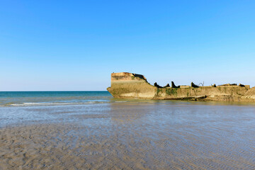 Une partie des éléments flottant du port artificiel de Arromanches les bains au niveau de Asnelles sur la plage de sable en France, en Normandie, dans le Calvados, au bord de la Manche.