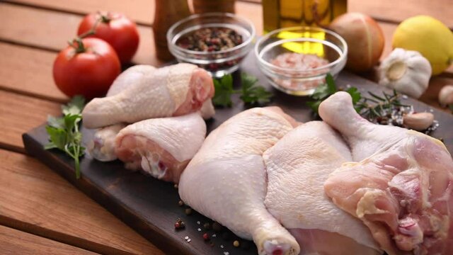Fresh raw chicken thighs with ingredients for cooking on a wooden cutting board
