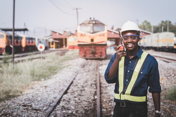 African machine engineer technician wearing a helmet, groves and safety vest is using a wrench to repair the train