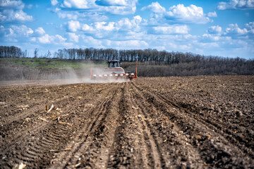 Fototapeta premium sowing work in the field. Tractor with seeder