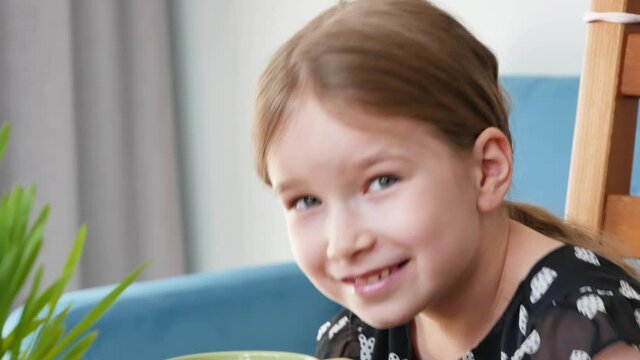 Little young girl, school age child laughing out loud at the table, portrait, face detail closeup. Childhood happiness, healthy cheerful smling kid, positive emotions simple lifestyle concept