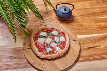 italian pizza margarita with basil and mozzarella on a wooden stand
