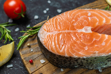 Raw salmon with spices and vegetables on the wooden board.