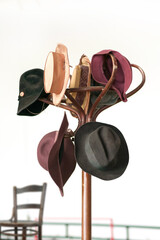 A variety of vintage colorful hats hanging on the wooden brown coat rack