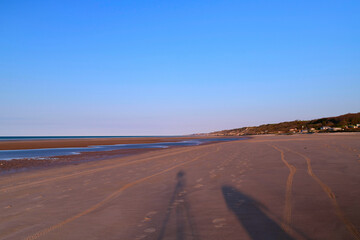La plage de sable de Omaha beach au coucher de Soleil et la silhouette d'un photographe en France, en Normandie, dans le Calvados, au bord de la Manche.