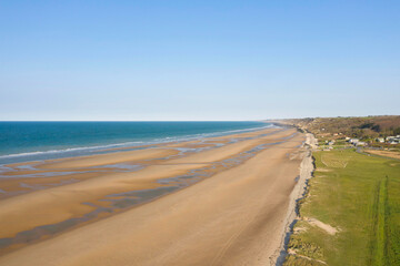 Fototapeta na wymiar La plage et la butte de galets de Omaha beach en France, en Normandie, dans le Calvados, au bord de la Manche sous le Soleil.