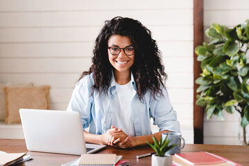 Successful young afro businesswoman working at her office desk. Front view of smiling african american female freelancer working at home