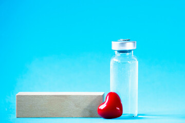 Safe vaccination concept. Glass vial with red heart on blue background.