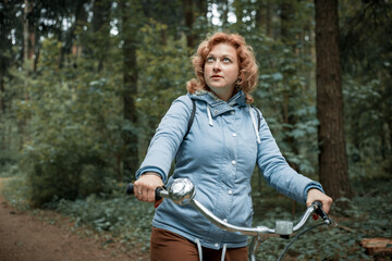 Naklejka na ściany i meble Blond woman with bike in the woods.