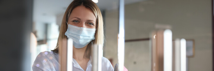 Portrait of smiling woman in protective medical mask opening door