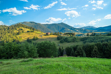 Obraz premium glade covered with grass on a background of hills and mountains at sunrise.