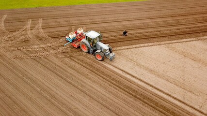 Landwirt mit Traktor und Sämaschine bei der Feldarbeit, Aussaat von Mais auf einem Acker, Landwirtschaft, Ernährung, Pflanzenanbau, Vogelperspektive © keBu.Medien
