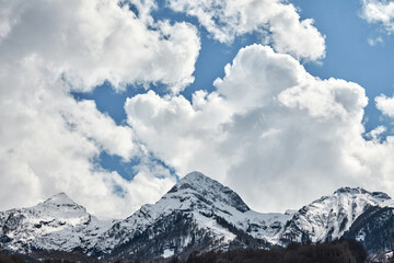 Snow-capped mountain peaks against a cloudy sky. Copy space.