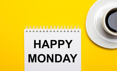 On a bright yellow background, a white cup with coffee and a white notepad with the words HAPPY MONDAY