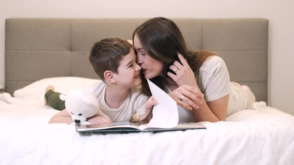 Happy mother and son reading book together on bed