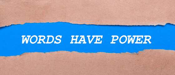 A strip of blue paper with the inscription WORDS HAVE POWER between the brown paper. View from above