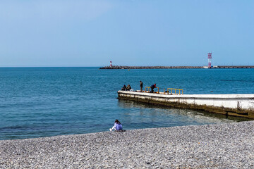 Sochi, Russia, April 13, 2021. People catch fish from the breakwater on the Black Sea coast