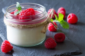 Delicious dessert panna cotta with raspberry sauce, fresh raspberries and mint on black slate...