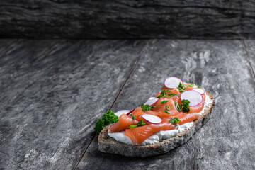 Healthy toast with rye bread and salmon on wooden table