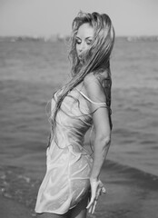 Black and white photo of beautiful blonde woman posing on the beach 