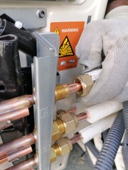 An air conditioning technician checking the flared copper before coupling it to the ac unit machine
