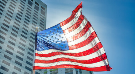 Backlit waving american flag with modern city skyscrapers in the background