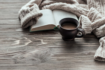 Morning coffee. Cup of coffee on a wooden table and a warm sweater on a background of yellow flowers Copy space.