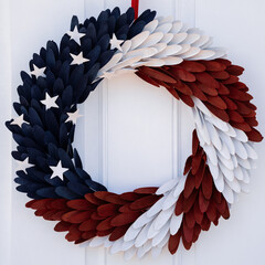 Photograph of a red, white and blue door wreath with stars symbolizing an American flag hung on a...