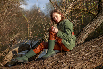 Beautiful lady in rustic style clothes on tree by the river