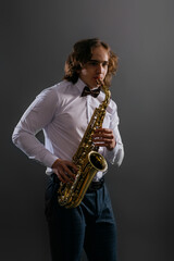 Obraz na płótnie Canvas Studio portrait of young cool man with saxophone on dark background.