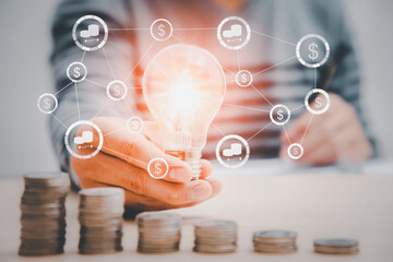 thinking and creative concept, businessman hand holding light bulb with coins stacking on desk.saving energy and money,The idea of ​​inspiration from online technology.innovation idea concept.