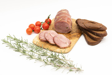 Baked Turkey roll with herbs, tomatoes and brown bread on a wooden background.