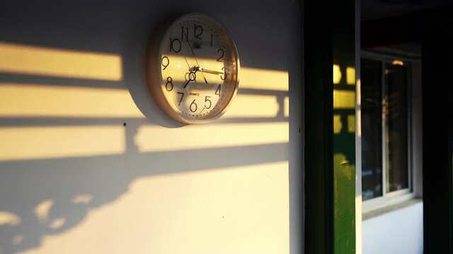 Time-lapse of a clock moving fast with shadow formed by sun shining on a wall of a house