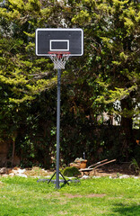 Outdoor Basketball ring costs in a garden on a grass against the background of green trees. Sports in the country. Photo of a backboard, Basketball hoop.