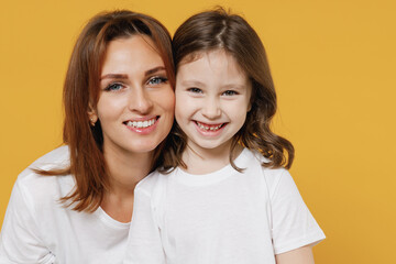 Happy woman in basic white t-shirt have fun with cute child baby girl 5-6 years old smile. Mommy little kid daughter isolated on yellow orange color background studio Mother's Day love family concept