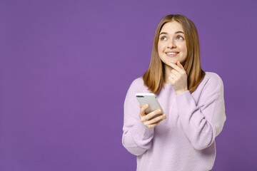Young dreamful pensive wistful excied student caucasian woman in purple sweater using mobile cell...