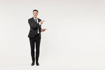 Full length young successful employee business corporate lawyer man in classic formal black grey suit shirt tie work in office point finger aside on workspace area isolated on white background studio. - obrazy, fototapety, plakaty