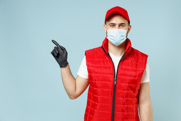 Delivery guy employee promoter man in red cap white t-shirt vest uniform sterile face mask gloves work courier service on lockdown coronavirus flu showing workspace isolated on pastel blue background.