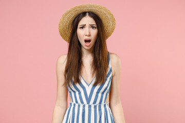 Young amazed impressed astonished caucasian woman in summer clothes striped dress straw hat looking camera with open mouth isolated on pastel pink background studio portrait. People lifestyle concept.
