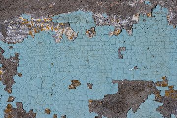 Peeling paint on the wall. Old concrete wall with cracked flaking paint. Weathered rough painted surface with patterns of cracks and peeling. Grunge texture for background and design. High resolution.