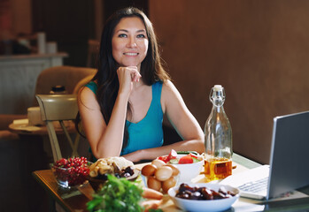 Woman eating healthy food at the table with laptop