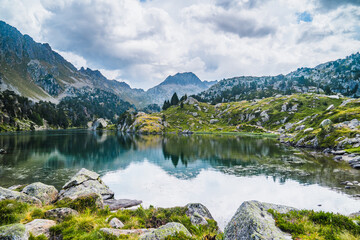 Landscape of mountain lake surrounded by mountains reflected in the water. Concept of mountain trip, summer vacations and nature. Circo Saboredo, Aran Valley-Pyrenees, Catalonia, Spain.