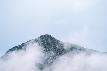 Misty foggy mountain landscape with copyspace in gloomy morning atmosphere. Dark tone, bad weather and cloudy day.