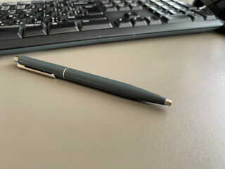 Automatic green ballpoint pen for writing on desktop office desk with computer keyboard. Business work