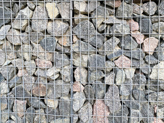 Texture of metal wire mesh and large stones cobblestones inside. The background